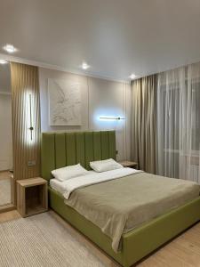 um quarto com uma cama grande e uma cabeceira verde em Уютная, новая квартира в центре города em Qostanay