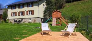 due sedie sedute su una terrazza in legno con una casa di 2chałupy - apartamenty w Soli a Sól