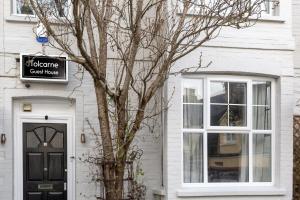 una casa blanca con una puerta negra y un árbol en Tolcarne Guest House, en Newquay