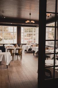 una sala da pranzo con tavoli, sedie e finestre di Brøndums Hotel a Skagen