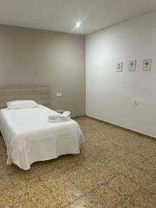 a bedroom with a white bed and a wall at Pensión Arnedo in Arnedo