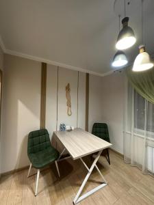 uma sala de jantar com uma mesa e duas cadeiras verdes em Уютная, новая квартира в центре города em Qostanay