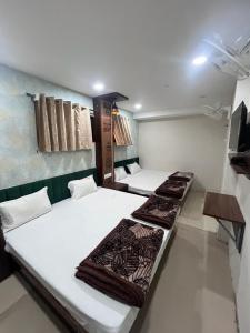 Habitación con 2 camas y TV en la pared. en Green leaf Hotel en Ujjain