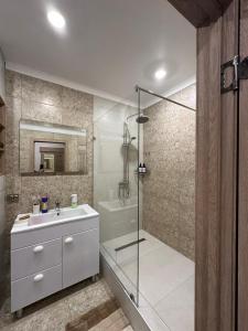 uma casa de banho com um chuveiro, um lavatório e uma banheira em Уютная, новая квартира в центре города em Qostanay