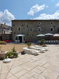 patio z krzesłami i parasolami przed budynkiem w obiekcie les cigales, studio laurier w mieście Grospierres