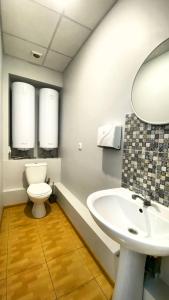 y baño con aseo, lavabo y espejo. en Uneed Rooms M1 en Kiev