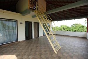 a wooden ladder in a room with a large window at Gokarna villa Tondavali in Achra