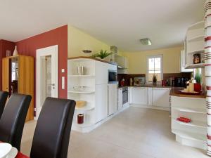 a kitchen with white cabinets and black chairs at Villa Harmony in Glowe