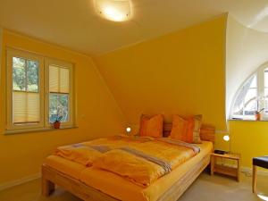 a bedroom with a bed with yellow walls and windows at Villa Harmony in Glowe