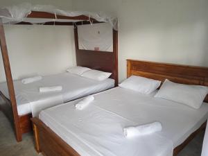 2 camas en una habitación con sábanas y almohadas blancas en Rangani Lagoon Resort, en Kalpitiya