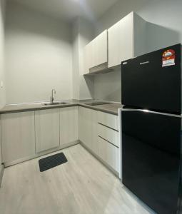 een keuken met een zwarte koelkast en witte kasten bij J&H JESSELTON QUAY lSLAND TRIP in Kota Kinabalu