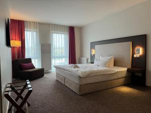 a hotel room with a large bed and a chair at Fontane Hotel in Schorfheide