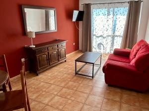 a living room with a red couch and a table at Apartamentos Balcón de Maro in Maro