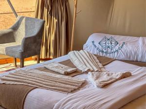 a bed with towels and a chair in a room at Rum Crystal Luxury Camp in Wadi Rum