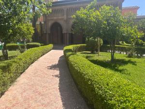 a walkway in front of a building with bushes at Riad Hicham in Marrakesh