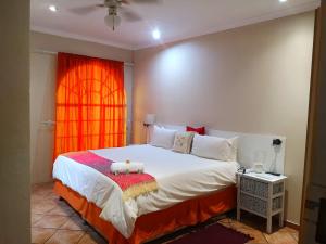 1 dormitorio con 1 cama grande y ventana de color naranja en Elsje's Country Inn, en Kempton Park