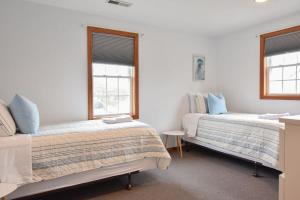 a bedroom with two beds and two windows at 12217 - Beautiful Views of Cape Cod Bay Access to Private Beach Easy Access to P-Town in Truro