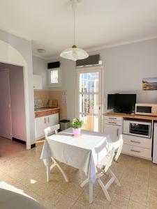 een keuken met een tafel met een witte tafeldoek erop bij Petit appartement tranquille avec jardin - Hyeres Centre Ville in Hyères