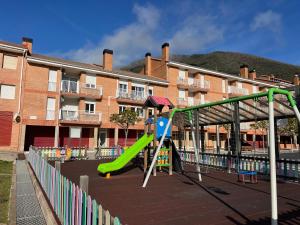 a playground with a slide in front of a building at Apartament acollidor al Berguedà 6p in Sant Jordi de Cercs