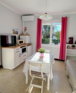 a living room with a table and a kitchen at Petit appartement tranquille avec jardin - Hyeres Centre Ville in Hyères