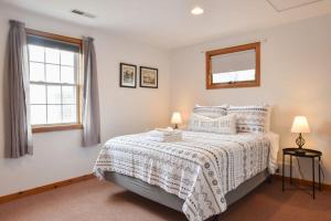 um quarto com uma cama com uma colcha branca e uma janela em 12215 - Beautiful Views of Cape Cod Bay Access to Private Beach Easy Access to P-Town em Truro
