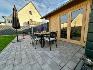 a patio with a table and chairs and an umbrella at Chalet Lasserg in Münstermaifeld
