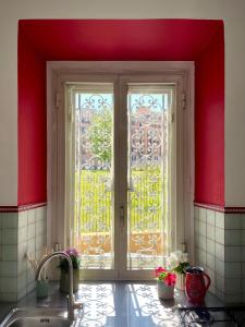 a kitchen with a sink and a window with red walls at Casetta Roma San Giovanni in Rome +11 photos