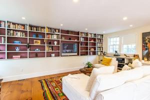 una sala de estar con muebles blancos y estanterías en Sunroom 1 3 Miles to Longnook Beach, en Truro