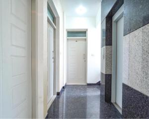 a hallway with white doors and black tiles at FabExpress Kings Suites in Bangalore