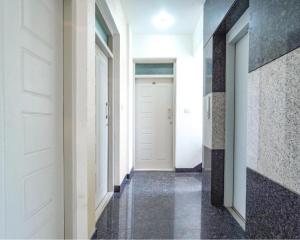 a hallway with white doors and black tiles at FabExpress Kings Suites HRBR Layout - Nr Manyata Tech Park in Bengaluru +19 photos