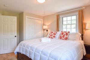 um quarto com uma grande cama branca com almofadas vermelhas em Private Patio Walk to Commercial St em Provincetown