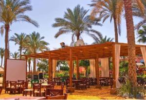 a wooden pavilion with tables and palm trees at شاليه بالميرا العين السخنة للعائلات فقط in Ain Sokhna
