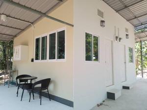 eine Terrasse mit Stühlen, einem Tisch und Fenstern in der Unterkunft บ้านรัญจวนสาขาสมุย in Ban Ko Khwan