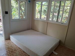 a large bed in a room with two windows at บ้านรัญจวนสาขาสมุย in Ban Ko Khwan