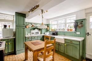 eine Küche mit grünen Schränken und einem Holztisch in der Unterkunft Georgian house in Billericay - quirky & homely in Billericay