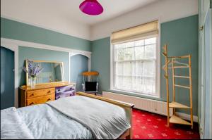 ein Schlafzimmer mit einem Bett, einer Kommode und einem Fenster in der Unterkunft Georgian house in Billericay - quirky & homely in Billericay