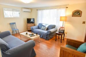 ein Wohnzimmer mit einem blauen Sofa und einem Stuhl in der Unterkunft Walk to Private Beach Dogs Welcome in Eastham