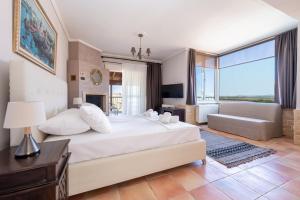 a bedroom with a large white bed and a couch at Villa Natura by RentalsPro Services - Nea Flogita Halkidiki in Flogita
