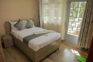 een slaapkamer met een groot bed en een raam bij Meirah Gardens Naivasha in Naivasha