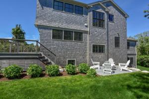 a house with two chairs and a table in the yard at Gorgeous Architectural Home w Water Views in Eastham +35 photos