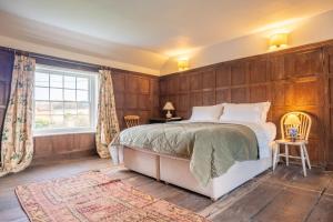Kersey的住宿－River House，一间卧室设有木镶板墙和一张床