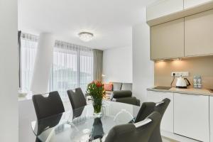 uma cozinha e sala de jantar com uma mesa de vidro e cadeiras em Wave Private Apartment 6th Floor em Międzyzdroje