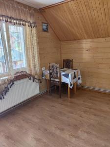 ein Zimmer mit einem Tisch und Stühlen in einer Hütte in der Unterkunft ГІРСЬКІ ПОДОРОЖі in Slawske