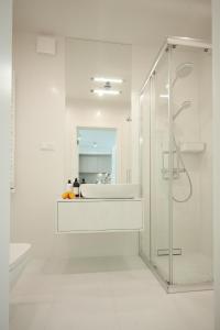 uma casa de banho branca com um lavatório e um chuveiro em Wave Private Apartment 6th Floor em Międzyzdroje