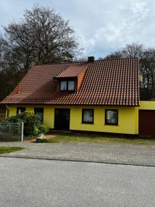 a yellow house with a red roof at FeWo 1 Am Sportplatz 2 in Ueckeritz