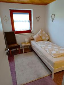 una camera con un letto e una sedia e una finestra di Ferienwohnung Schleßmann a Isny im Allgäu