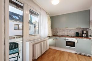 a kitchen with white cabinets and a large window at Hummerklippen Apartments in Helgoland