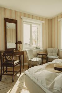 a bedroom with a bed and chairs and a mirror at Brøndums Hotel in Skagen
