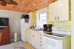 a kitchen with white appliances and a wooden ceiling at Bright Cottage Close to Bayside Beaches in Eastham +17 photos