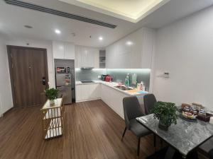 una cocina con armarios blancos y una mesa con sillas. en Apartment Hilton Luxury, en Hai Phong
